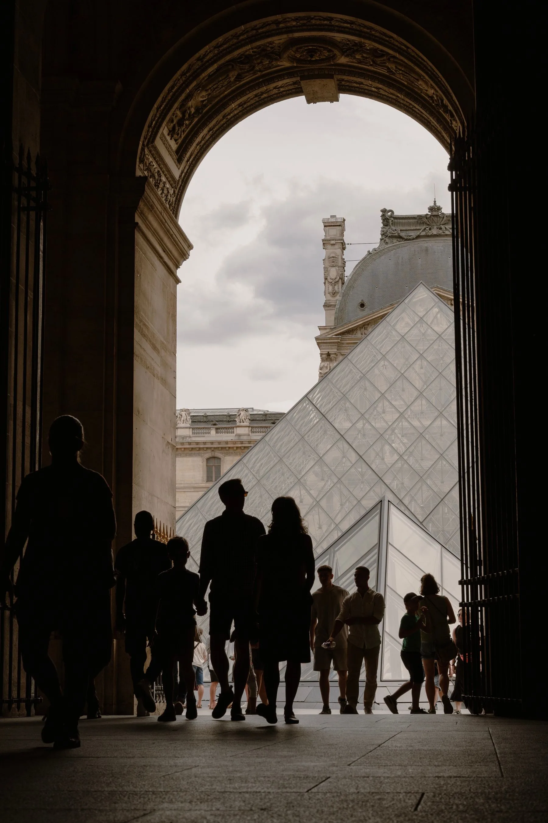 Visitantes entrando al Museo del Louvre frente a su pirámide de cristal